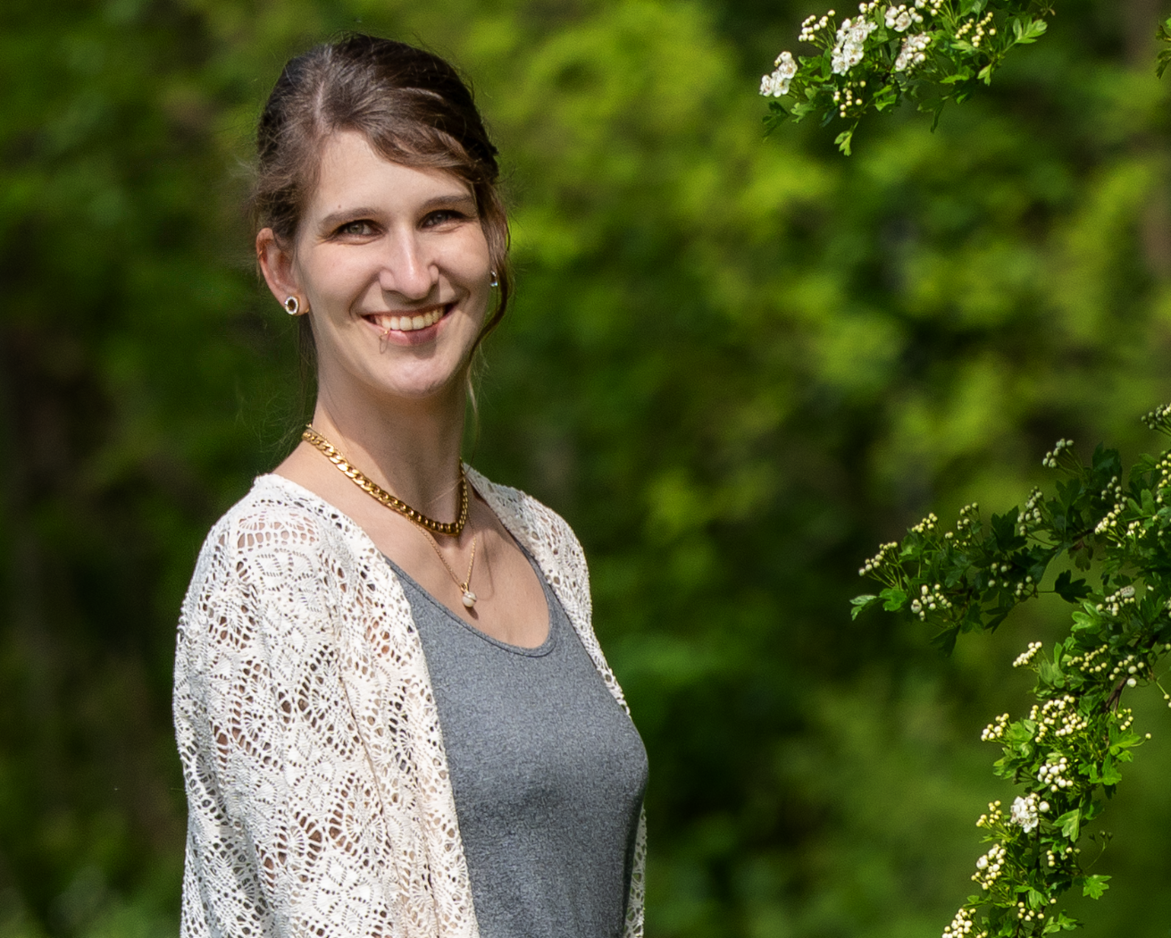 Portrait Denise Nickert Foto der Trageberaterin Denise, sie lächelt in die Kamera und steht im Grünen neben einem Baum